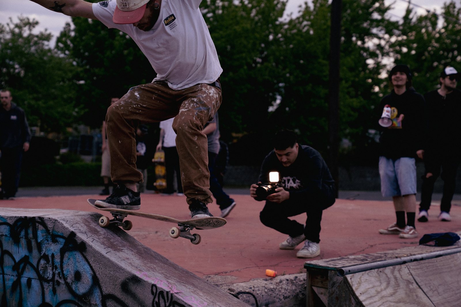 Skater mid-trick on a ramp at dusk while a filmer captures the session